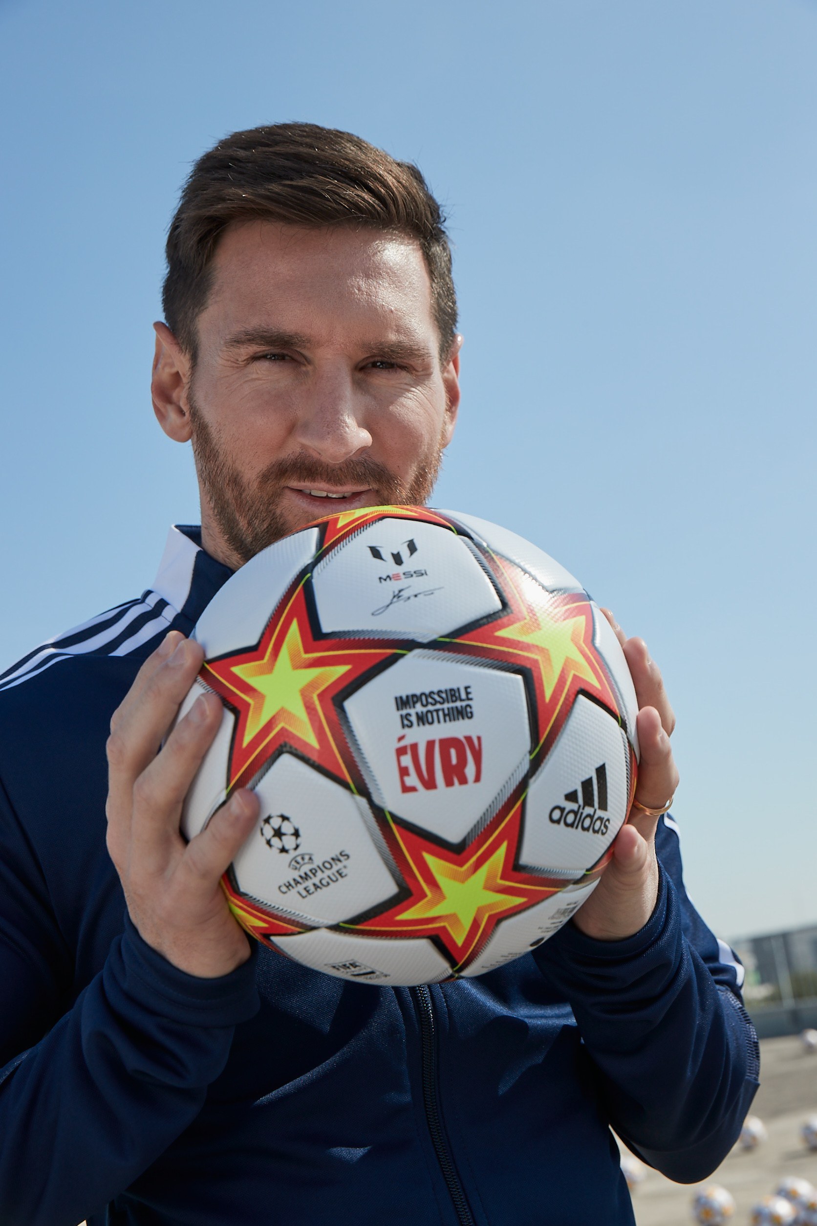 Lionel Messi tient un ballon « Impossible is nothing Évry »