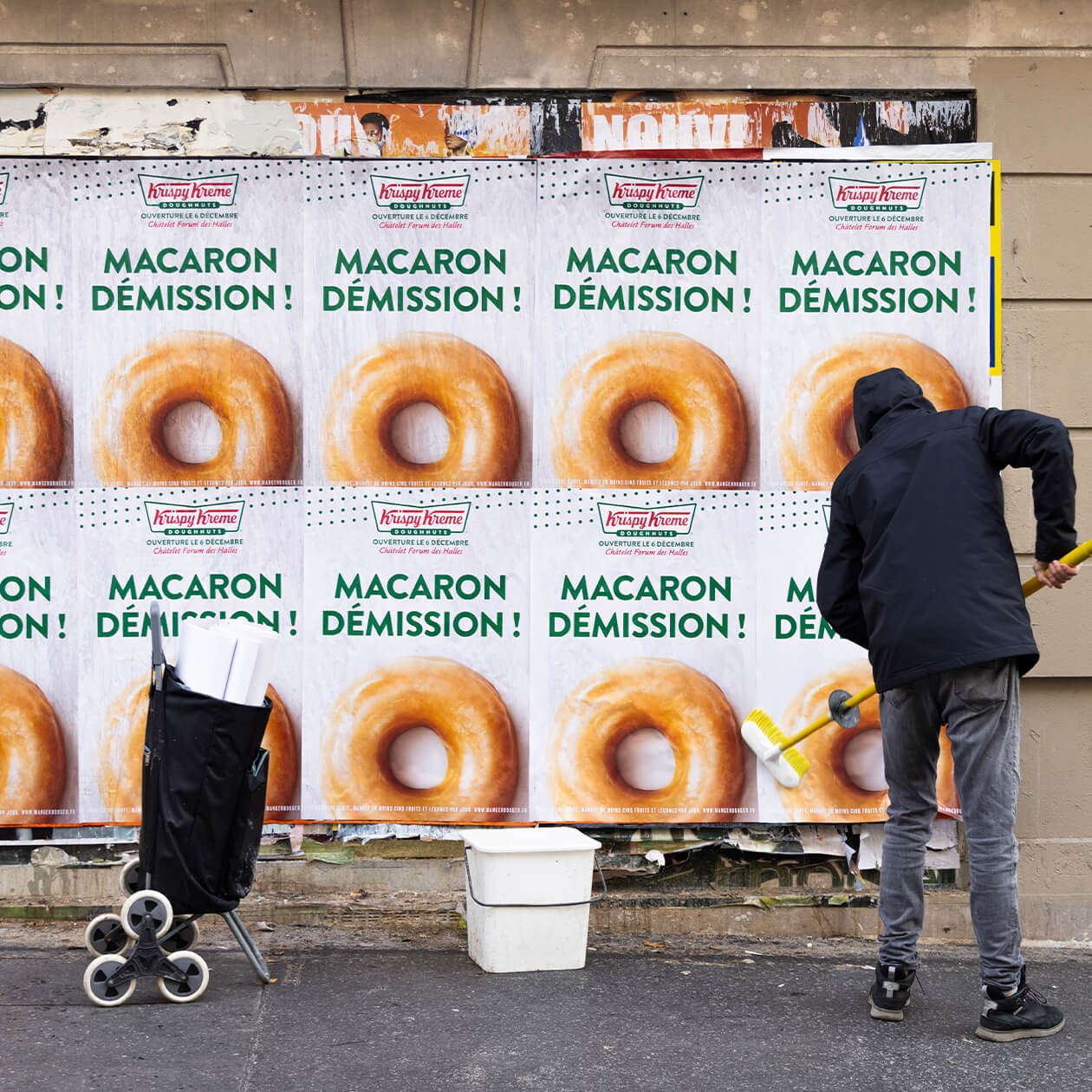 Affiches « Macaron démission ! » collées dans la rue, un colleur passe la brosse