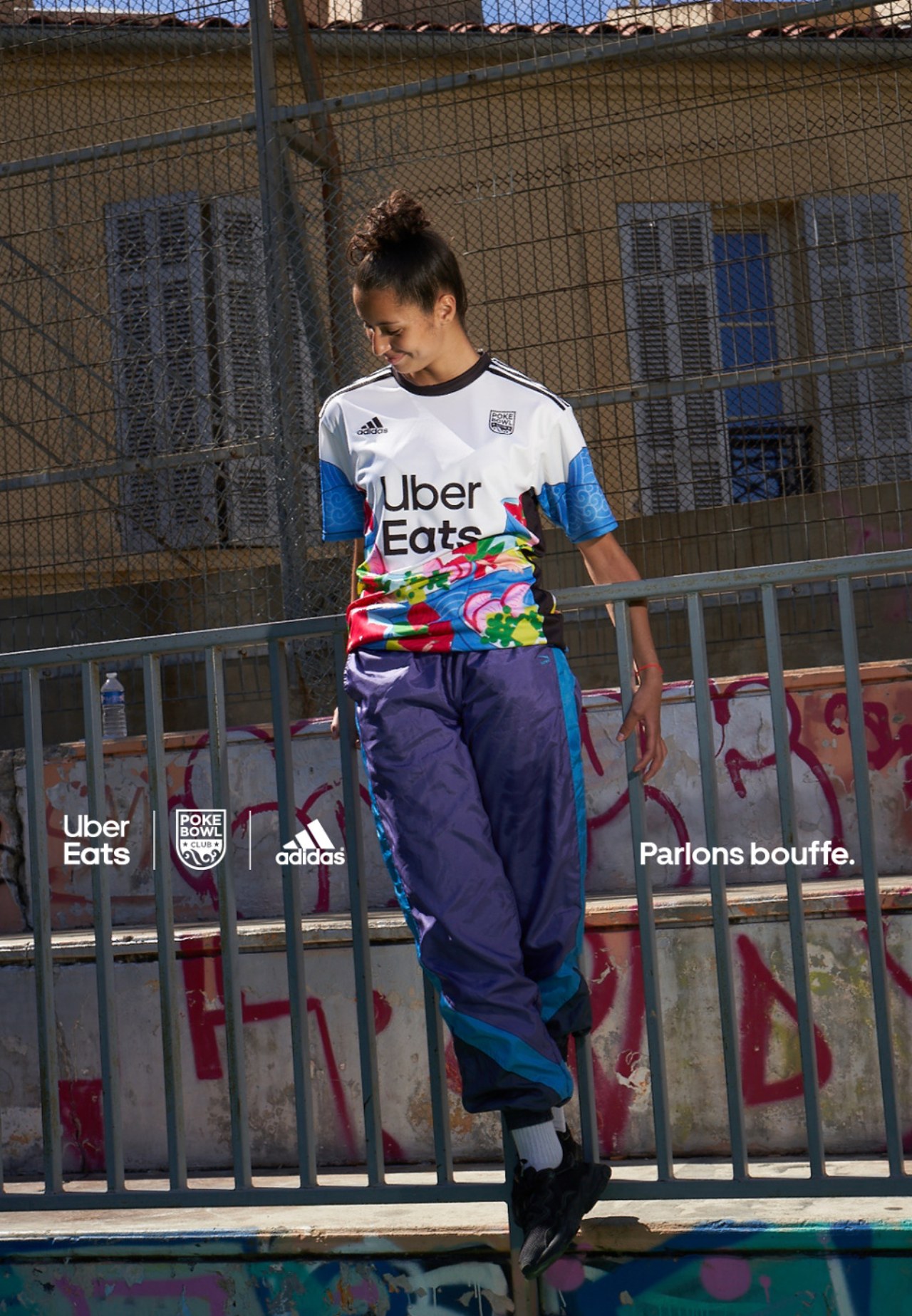 Joueuse en maillot Uber Eats × Adidas multicolore, appuyée à une grille