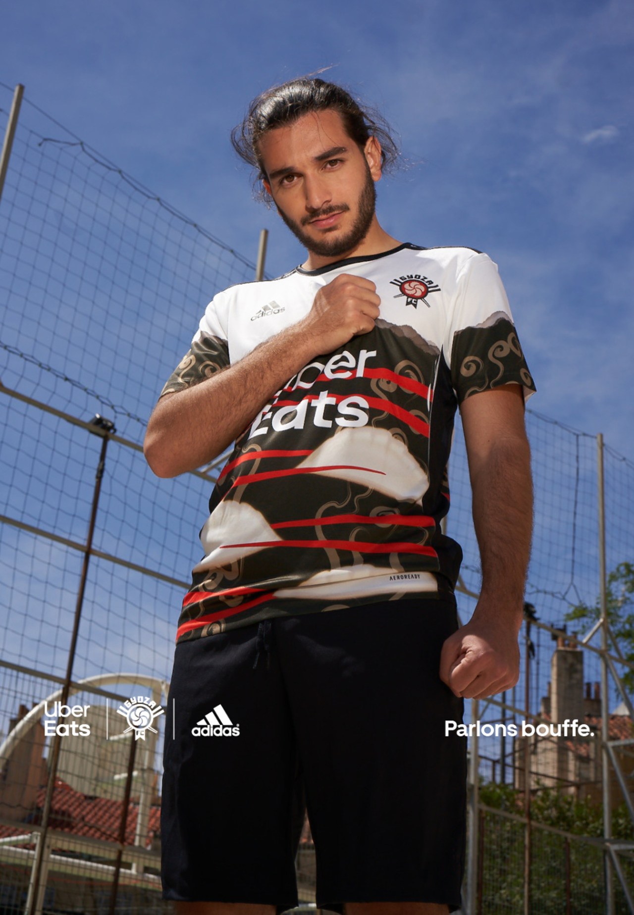 Joueur en maillot noir et blanc Uber Eats × Adidas, ciel bleu en arrière-plan